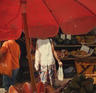 Street market scene under red umbrella showing fruit vendors and shoppers at Port Louis Central Market, Mauritius