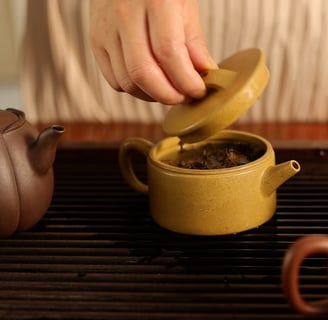 A hand lifting the lid off a teapot, revealing tea inside