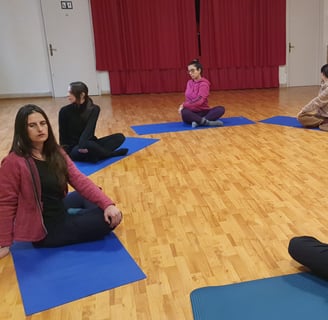 a group of people sitting on yoga mats in a circle, classe di esercizi di bioenergetica
