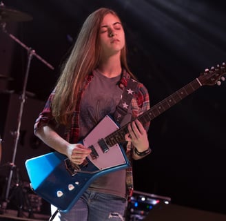 Gurnee Guitar Academy Guitar Lessons a girl playing guitar in a concert
