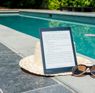a tablet with a straw hat and sunglasses next to a book