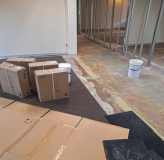 Office interior in early renovation phase with floor preparation and drywall framing.