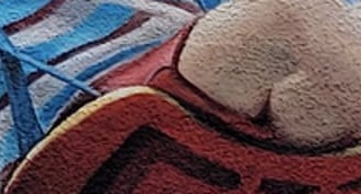 Fresque sur façade. Un garçon joue sur une balançoire au-dessus d'une pile de livres.