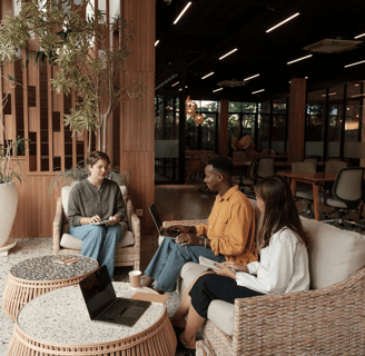 a group of people sitting around a table talking and taking notes