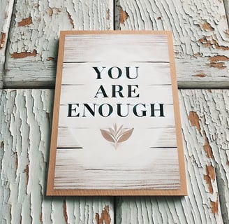 Inspirational wooden sign reading 'YOU ARE ENOUGH' against a peeling white painted wood background.