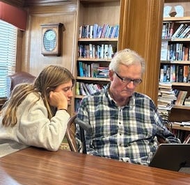 teen girl helping older man with his computer
