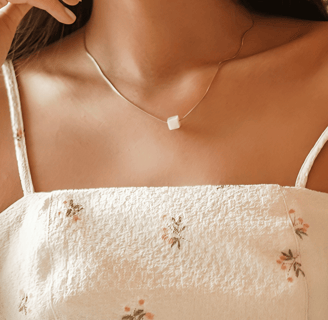 a woman in a white dress waering pearl pendant and earring