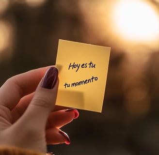 Mano femenina sostiene nota con frase "Hoy es tu momento", representa inspiración y empoderamiento para emprender.