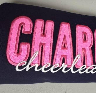 Custom glitter appliqué embroidery in pink & white thread on navy fabric – cheer spirit San Antonio