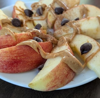 Apple slices made into a dessert nacho with peanut butter drizzle, chocolate chips and cinnamon