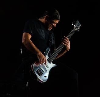 Robert Trujillo playing a guitar in a dark room