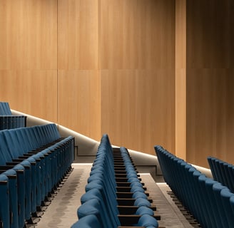 a wood clad auditorium with rows of blue chairs