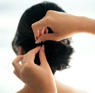 Hairstylist adding a bobby pin to the bride's hair.
