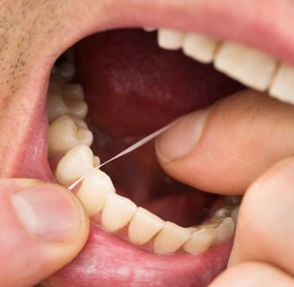 a man cleaning his teeth using dental floss