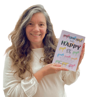 smiling woman with long brown hair and white sweater holding a book