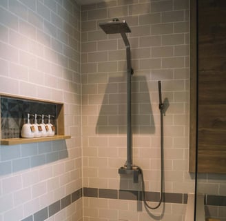 Walk-in shower with matte black fixtures and recessed shelf on subway-tiled wall