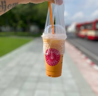 a person holding a cup of coffee in a plastic cup
