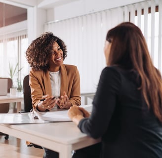due donne una di fronte l'altra che parlano e sorridono
