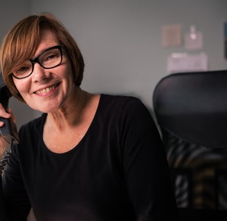 eine frau mit braunen haaren und brille spricht in ein telfon im atelier rohlfs