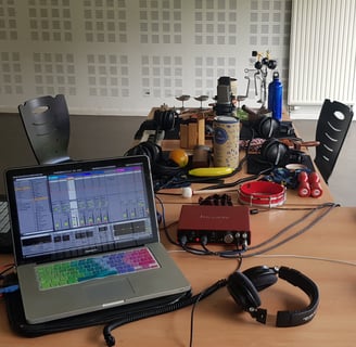 un ordinateur portable avec Ableton Live sur une table avec de nombreux objets sonores et instrument
