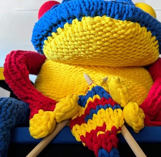 FROG knitting on Rietveld chair with giant knitting needles by Dundee & Lee