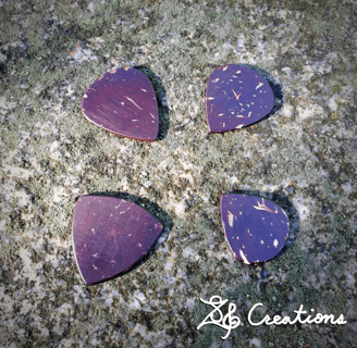 Four of our handmade guitar picks from coconut shell on a granite block.