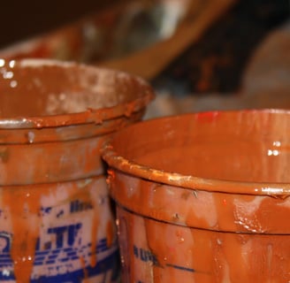 two buckets with paint and a paintbrush in the background