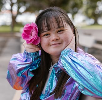 a beautiful young women with downs with a pink flower in her hair