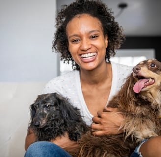 A beautiful young black woman holding her two elderly dogs
