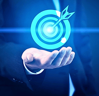 A businessman in a suit holds up a holographic image of a dart hitting a bullseye target, face unseen.