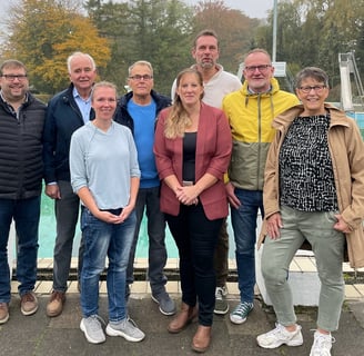 a group of people standing around a pool