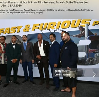 Dwayne Johnson with John Tui  in front of a fast & furious backdrop billboard 