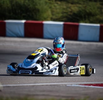 Kart blanc numéro 611 piloté par un compétiteur en combinaison blanche et casque chromé, manœuvrant un virage sur piste.