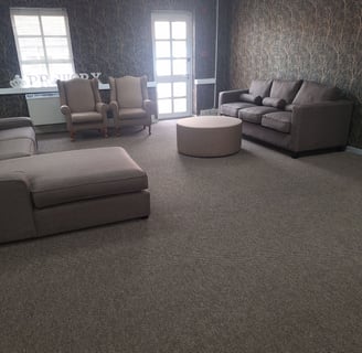 Finished lounge area with custom carpeting, blinds, and modern furnishings.