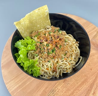 Mangkuk mie ayam dengan topping ayam, daun bawang, dan kerupuk pangsit di Depot Mie Ayam RATU