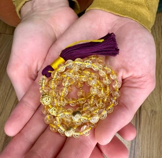 A handcrafted mala made with Citrine and Gold with purple tassel