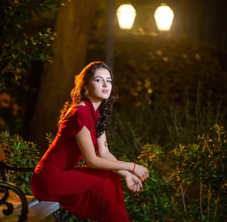 Night portrait photography in Budva Old Town: Woman in red dress seated on vintage bench, Budva