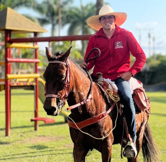a man in a red shirt and hat riding a horse