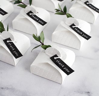 a table with a bunch of small white paper wedding favour boxes