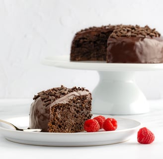 a slice of chocolate cake with chocolate frosting and raspberries