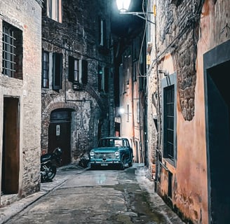 Photo of a vintage Italian car in an alley at night in Perugia, Italy.