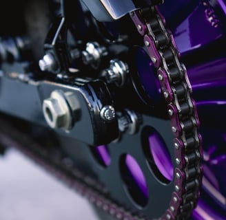 Black motorcycle sprocket with purple chain link and purple wheel