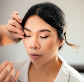 Makeup artist adjusting a false lash during application on the bride.