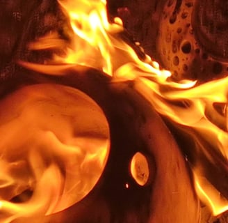 a pit fire with flames and pottery in the pit