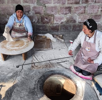 women baking traditional lavash bread in clay oven