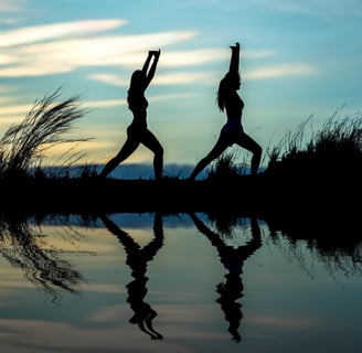 two people doing yoga poses in the evening