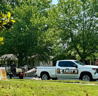 White truck with Troys Exterior cleaning logo and pressure washing trailer in tow