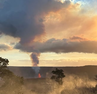 steam rising from vents caught in golden hour sunlight with kilauea eruption in the background