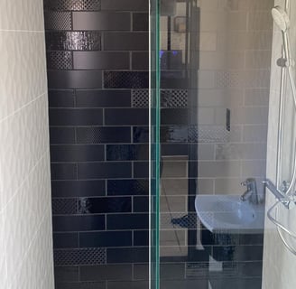Douche avec faïence métro noire à plusieurs motifs et retours en blanc texturé