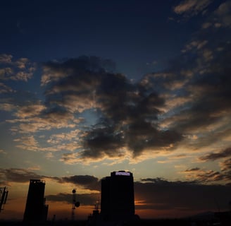 a sunset sky with a few clouds and a few buildings